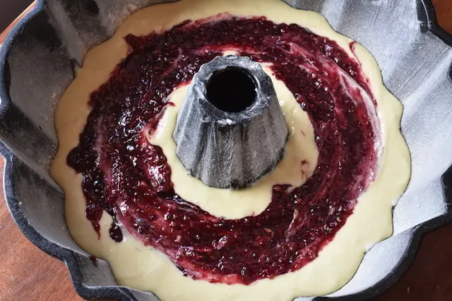 Bundt pan filled with batter and raspberry preserves