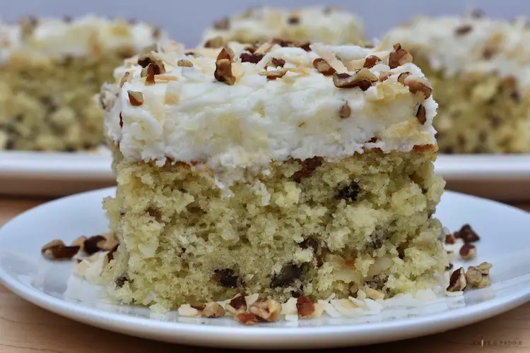 Cake on a plate topped with coconut and pecans