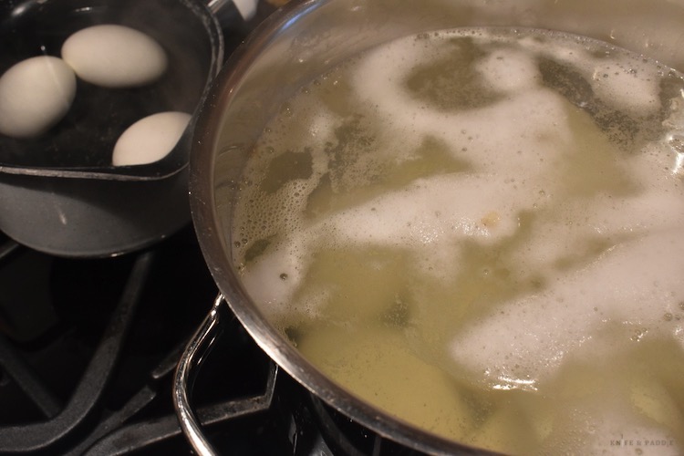 Potatoes and eggs boiling on stove