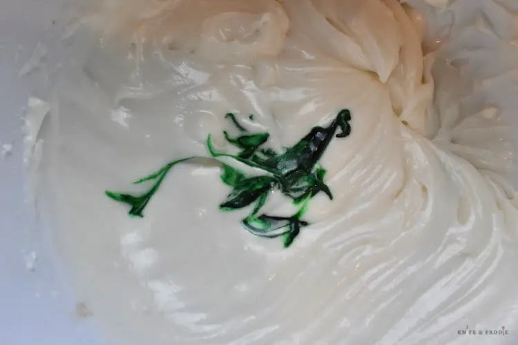 Adding green food coloring to the frosting 