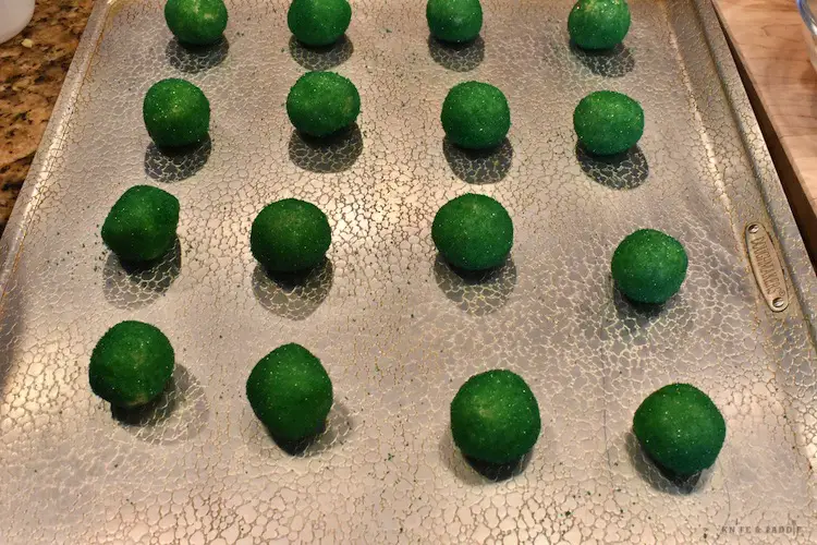 Dough balls rolled in green sugar on a baking sheet