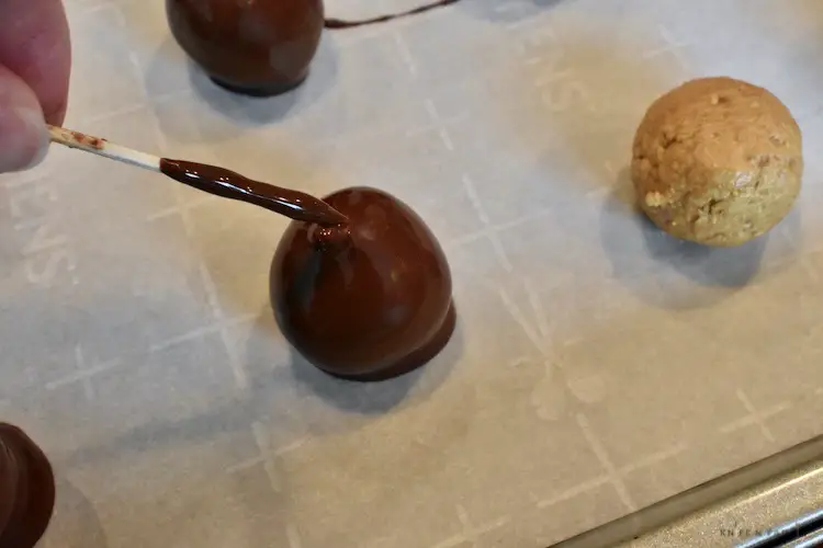 Chocolate dipped peanut butter ball on the parchment lined baking sheet