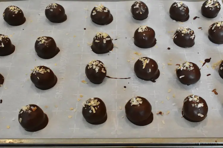 Chocolate dipped peanut butter balls on the parchment lined baking sheet