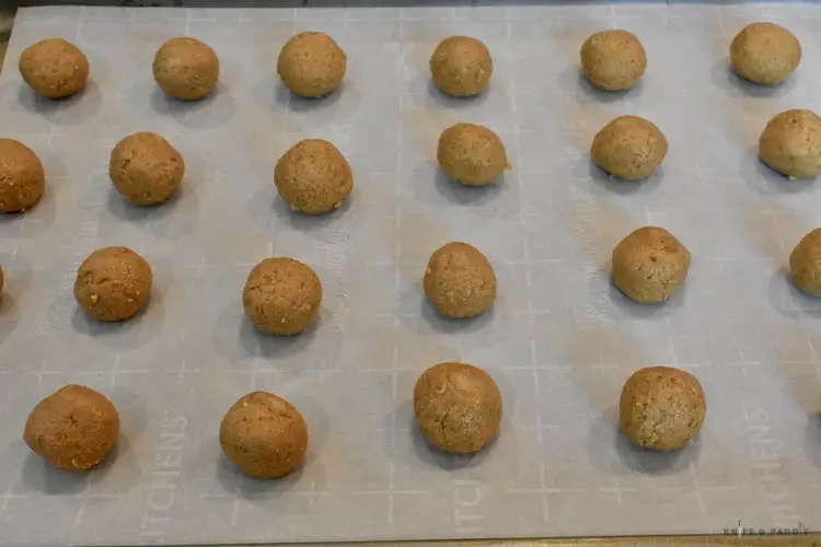 Rolled peanut butter balls on a parchment lined baking sheet