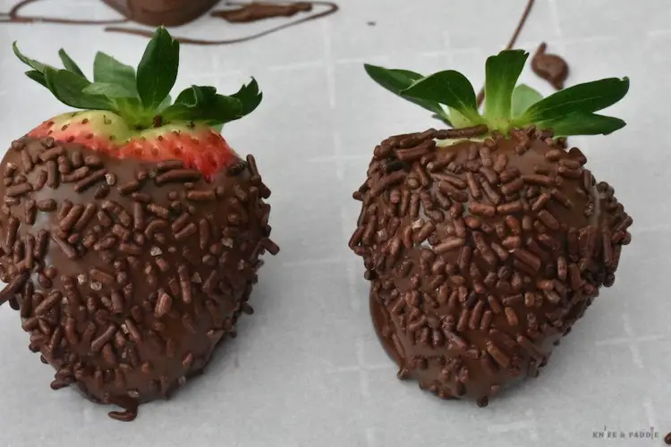 Chocolate covered strawberries with chocolate sprinkles on parchment paper