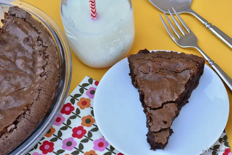 Double chocolate fudge pie in pie dish, slice on plate, and glass of milk