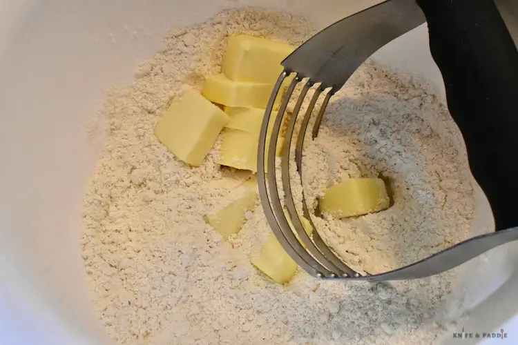 Flour, sugar, baking soda, salt in a bowl.  Cutting in butter