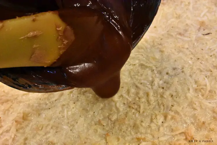 Pouring the chocolate peanut butter mixture over the hot coconut layer