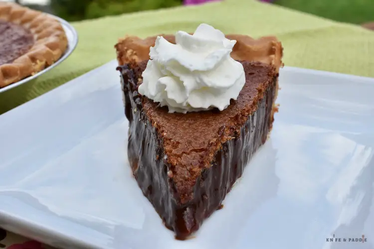Slice of chocolate chess pie with whipped cream plated