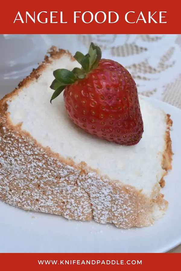 Slice of cake with a strawberry on top plated with powdered sugar