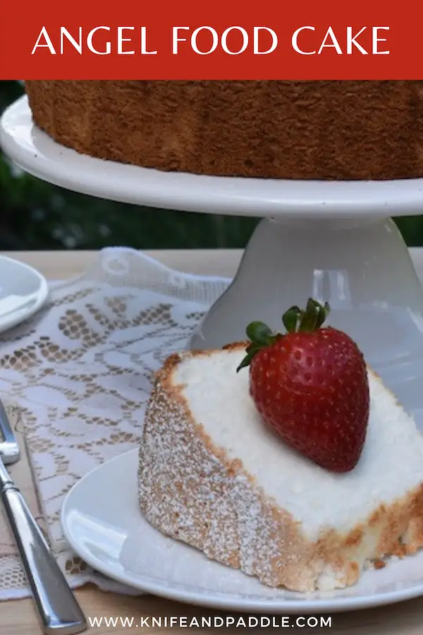 Angel Food Cake on a cake stand and a slice plated with a strawberry on top