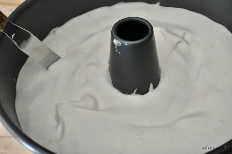 Angel food cake batter in a tube pan using a flat knife to break up air pockets
