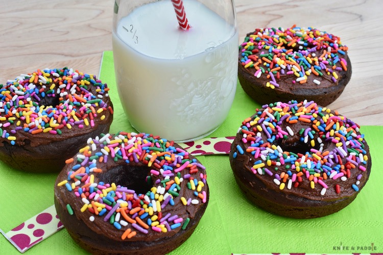 Double chocolate donuts with rainbow sprinkles and a jar of milk