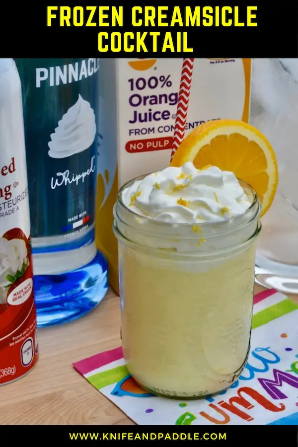 Ice, whipped vodka, orange juice, whipped cream, adult beverage in a mason jar with whipped cream and an orange slice and zest