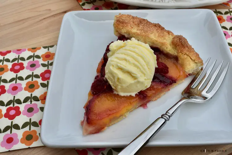 Slice of Plum and Raspberry Galette with vanilla ice cream on a plate