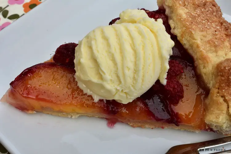 Slice of Plum and Raspberry Galette with vanilla ice cream on a plate