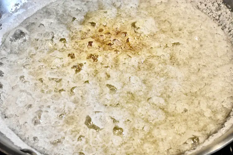 Sugar and water crystalizing in a pan while starting to turn amber