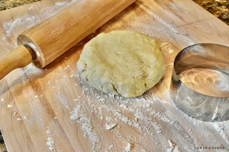 Rolling pin, floured board with pie crust and a 4 inch food ring
