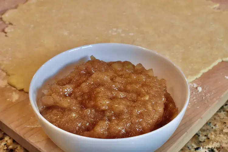 Rolled pie crust and a bowl of applesauce