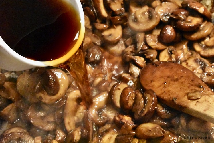 Marsala wine poured into a sauté pan filled with mushrooms