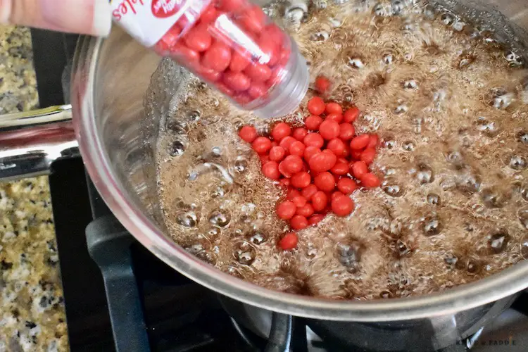 Red cinnamon candies, sugar, cinnamon, water and light Karo syrup in a saucepan boiling