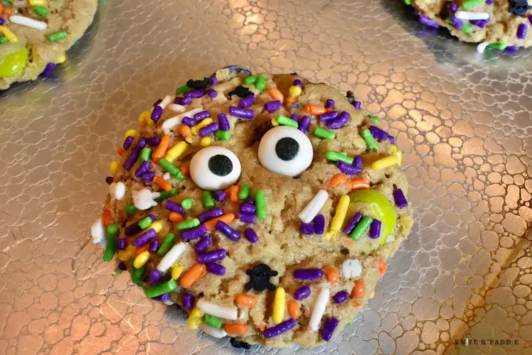 Pressing in the candy eyeballs on the cookie on the baking sheet