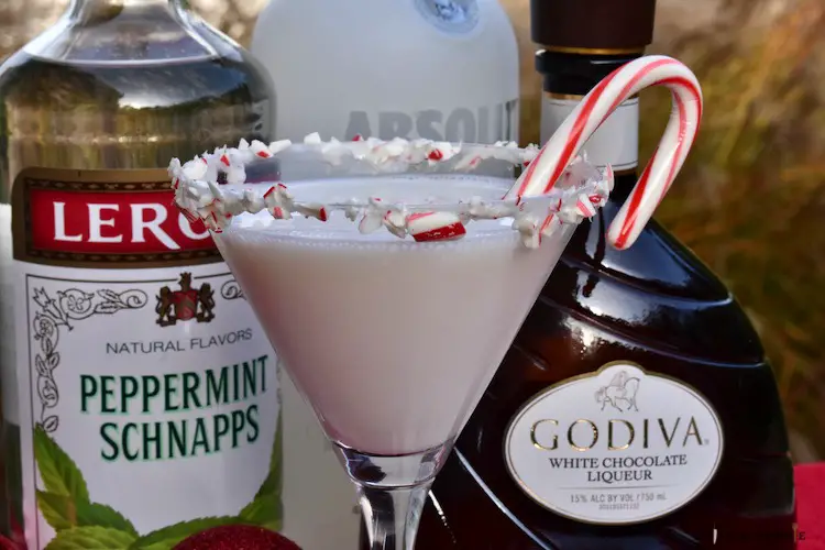martini with crushed candy canes and marshmallow topping on the rim with a candy cane for garnish