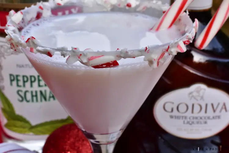 martini with crushed candy canes and marshmallow topping on the rim with a candy cane for garnish
