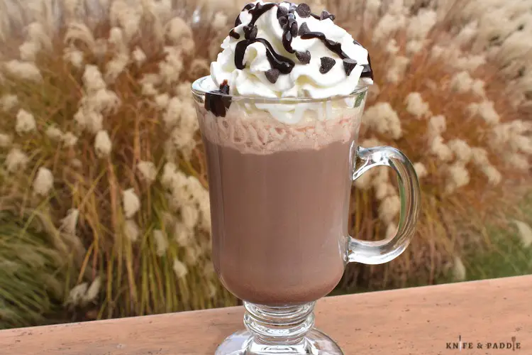Butterball Hot Chocolate in a glass with whipped cream, chocolate syrup and mini-chocolate chips