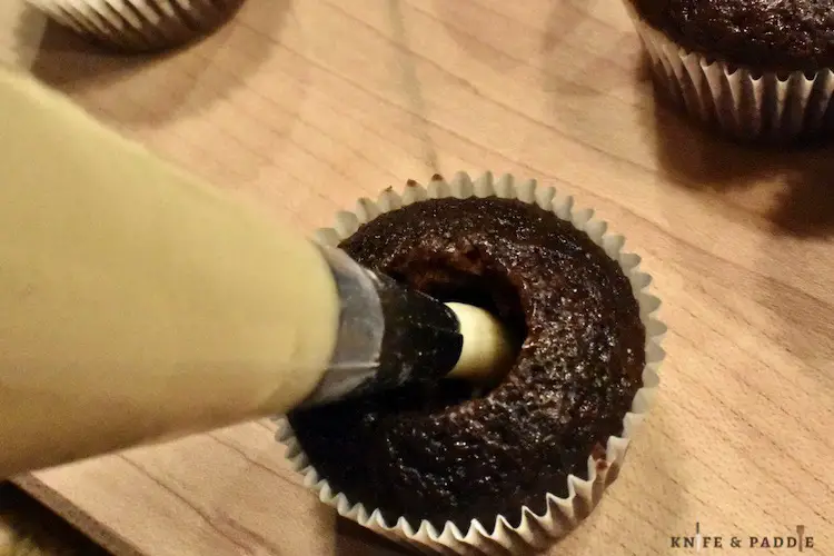 Using a piping bag filling the hallowed out cupcake hole