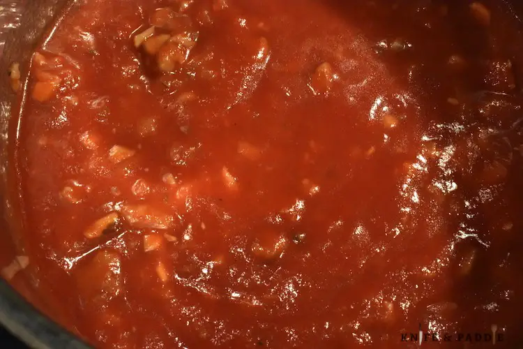 onions, sausage and tomato sauce in a sauce pan