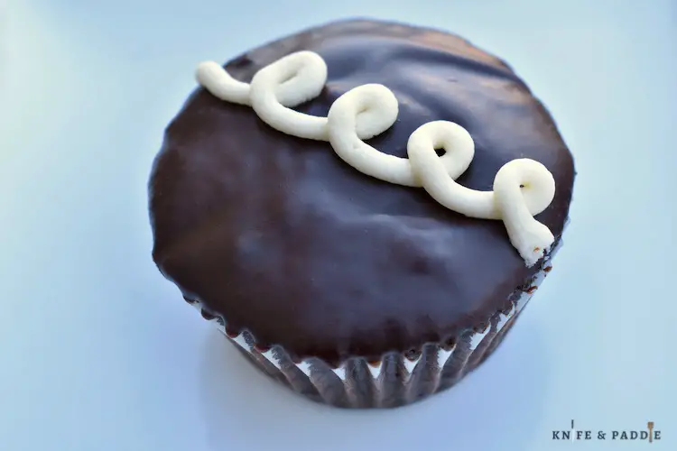 Dipped cupcake in chocolate ganache and topped with a vanilla iced loop