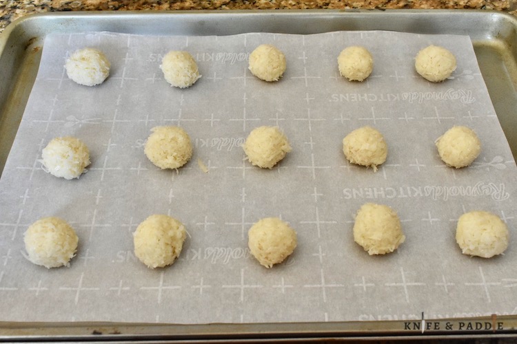 Raw coconut balls on a baking sheet lined with parchment paper