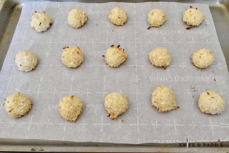 Baked coconut balls on a baking sheet lined with parchment paper