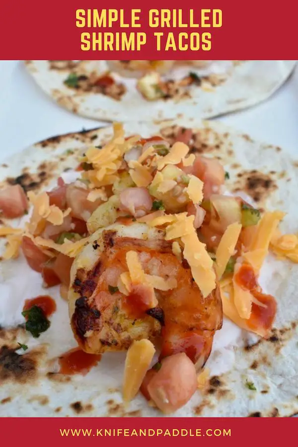 Grilled shrimp tacos with sour cream, salsa, sriracha and cheddar cheese on a toasted tortilla 