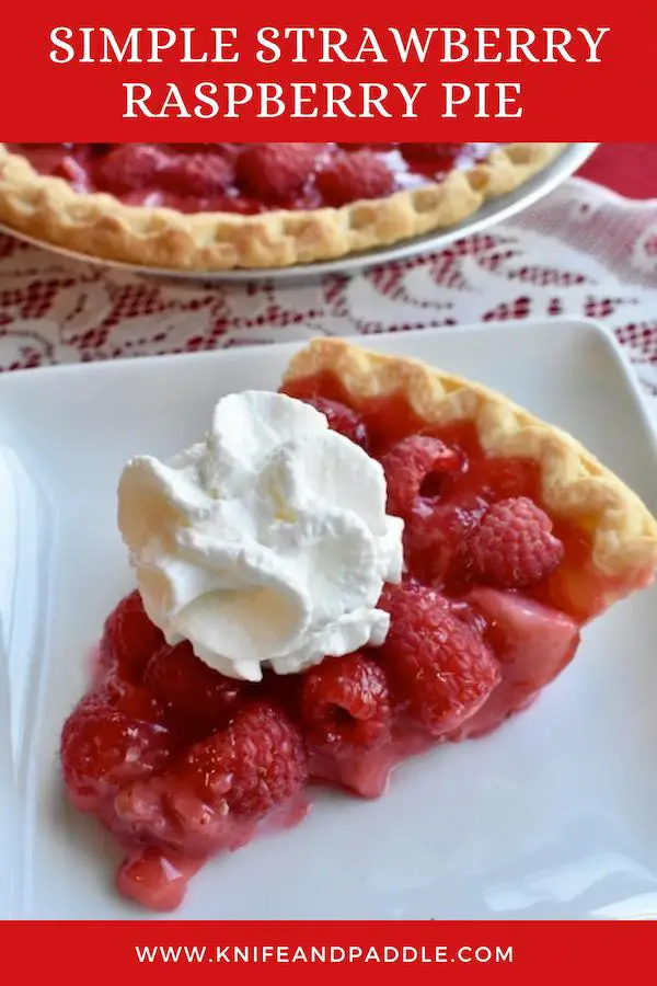Red fruit topped with whipped cream in a pie crust on a plate