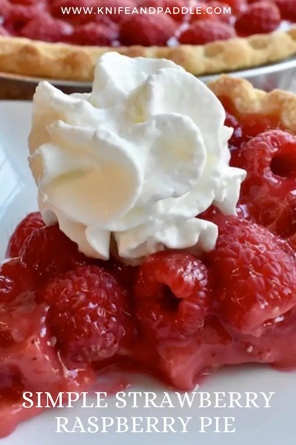 Red fruit topped off with whipped cream on a plate