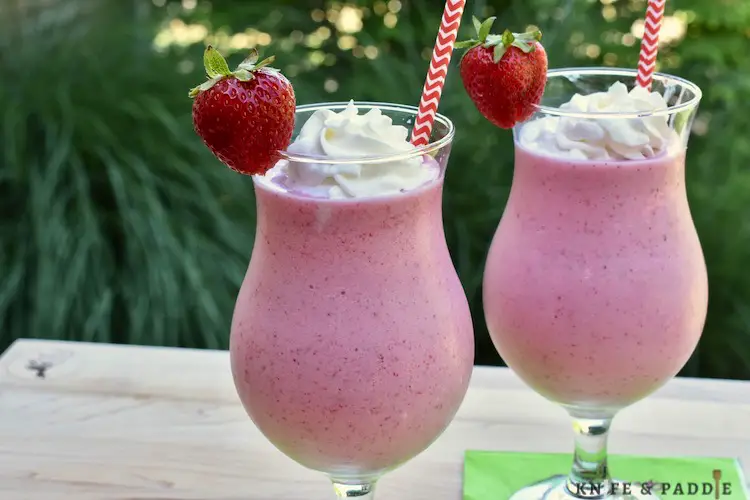 Frozen Strawberry Daiquiri Shakes in hurricane glasses topped with whipped cream and a strawberry