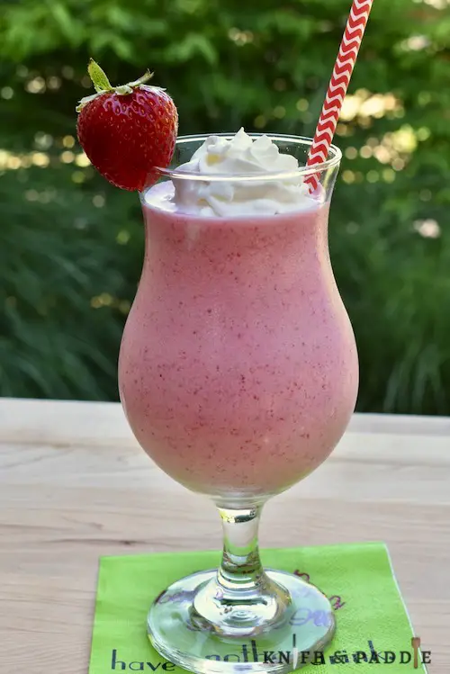Frozen Strawberry Daiquiri Shake in a hurricane glass with whipped cream and a strawberry