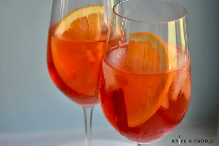 Orange liquor, prosecco, club soda and an orange slice in stemmed balloon glasses