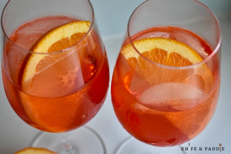 Orange liquor, prosecco, club soda and an orange slice in stemmed balloon glasses