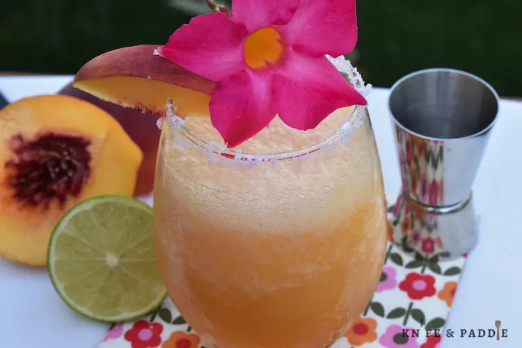 Peach Margarita in a cocktail glass garnished with a peach slice and flower