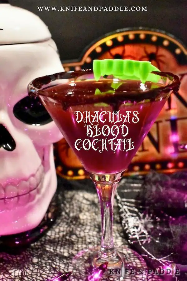 Dracula's Blood Cocktail in a blood dripped martini glass topped with bright green vampire teeth