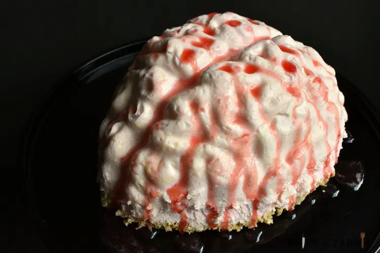 No-Bake Cheesecake Brain covered with strawberry sauce on a plate