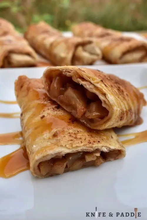 Apple Pie Enchiladas drizzled with caramel sauce in a plate