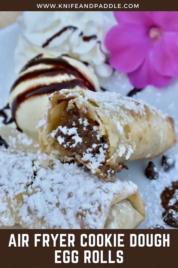 Air fryer cookie dough egg rolls covered with powdered sugar with a side of chocolate dipping sauce 