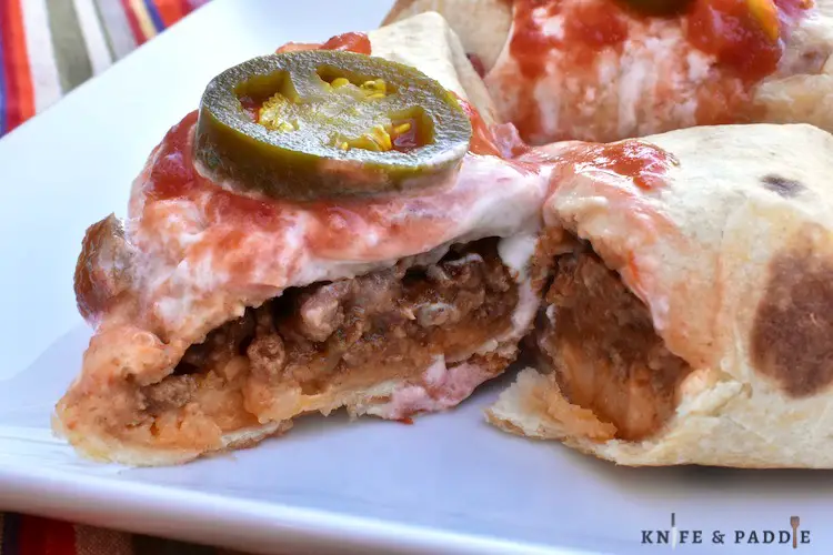 Air Fryer Beef Chimichangas on a plate with sour cream, jalapeños, and salsa