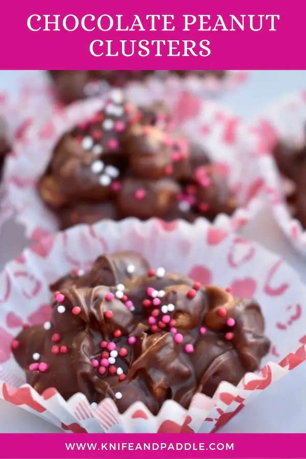 Chocolate Peanut Clusters on a plate with pink, white and red nonpareils in Valentine's Day wrappers