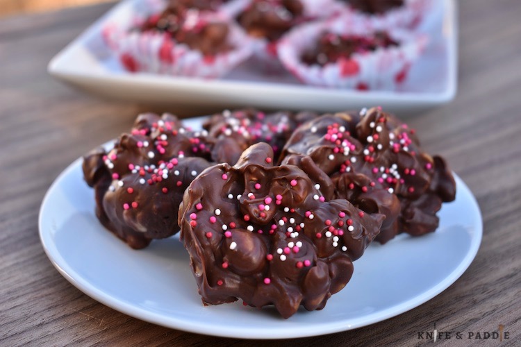 Chocolate Peanut Clusters on a plate with pink, white and red nonpareils 