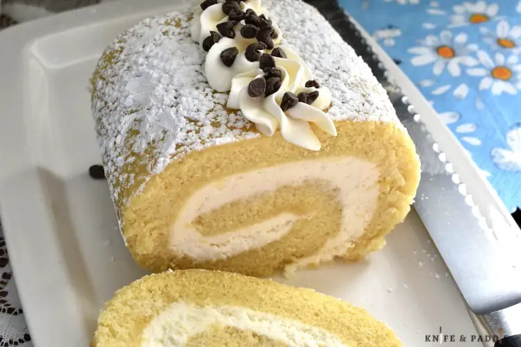 Cannoli Cake Roll pipped with frosting and topped with mini-chocolate chips